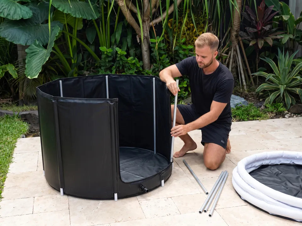 Un hombre montando la bañera de inmersión en frío en un patio